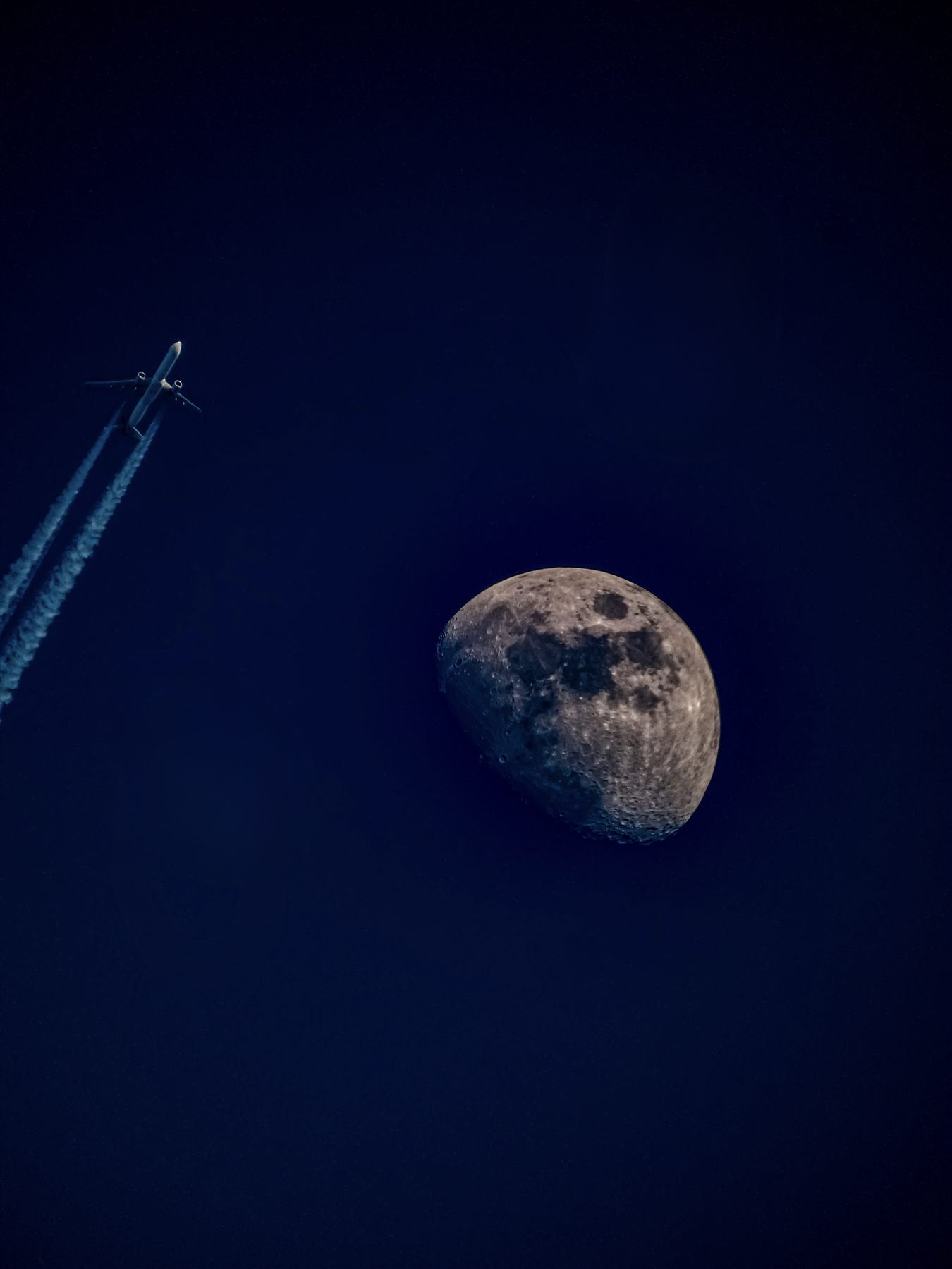 Avion de ligne et lune gibbeuse dans un ciel bleu nuit