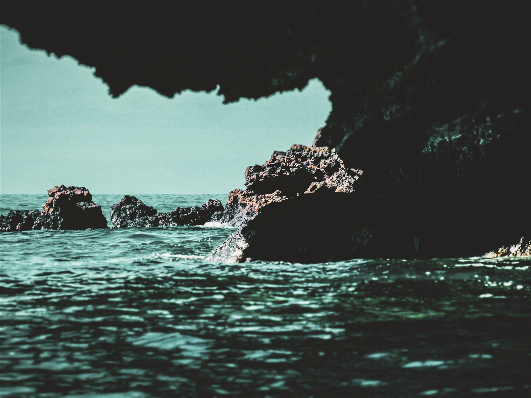 Roches sombres surplombant une mer verte et calme